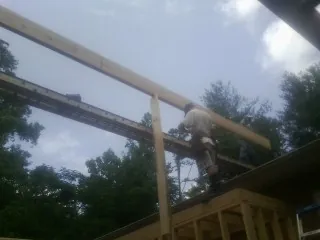 Carpenter setting a ridge beam over a new addition frame — Ice Dam Removal by Roofing Brothers in Modale
