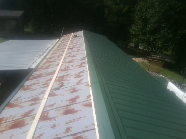Old rusted panels beside newly installed green metal roofing — Wind Damage Roof Repair by Roofing Brothers in Modale