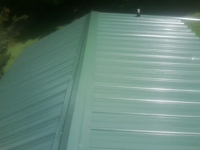 New green metal panels meeting at the ridge of a roof — Flat Roof Repair work by our crew in Modale