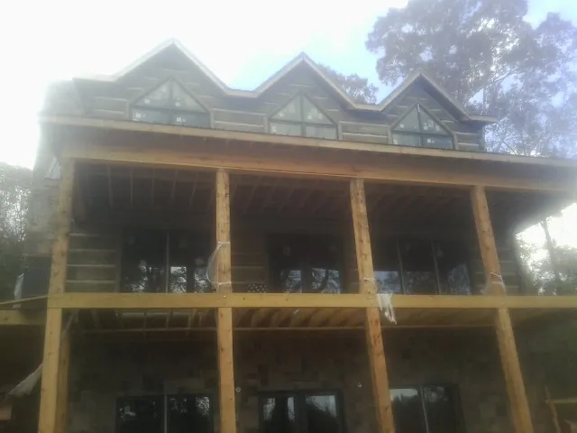 Dormers and porch framing on a large log home under construction — Roof Coating work by our crew in Modale