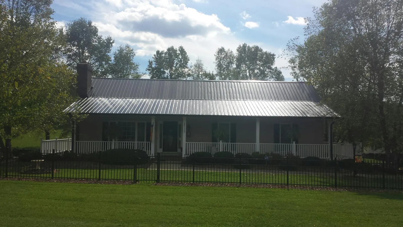 Gray metal roof on a brick ranch with a full width front porch — Gutter Guard Installation work by our crew in Modale