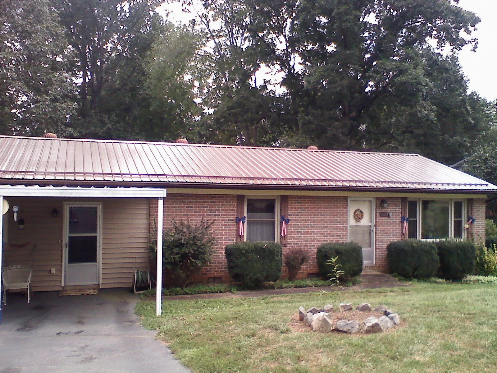 Bronze metal roof and carport on a brick ranch home — Roof Repair work by our crew in Modale