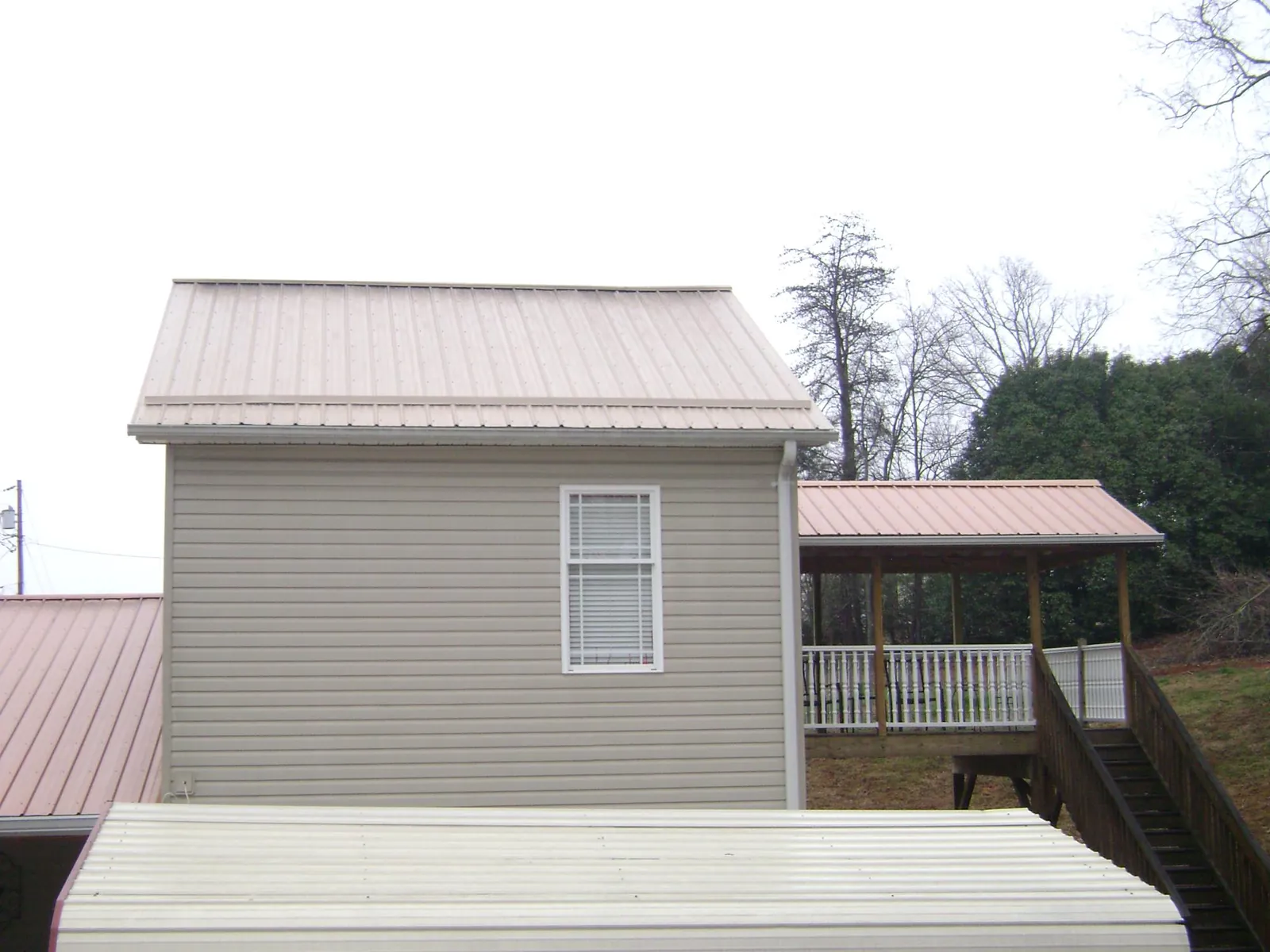 Tan metal roofs on a two story addition and attached porch, from a Roof Replacement job in Modale